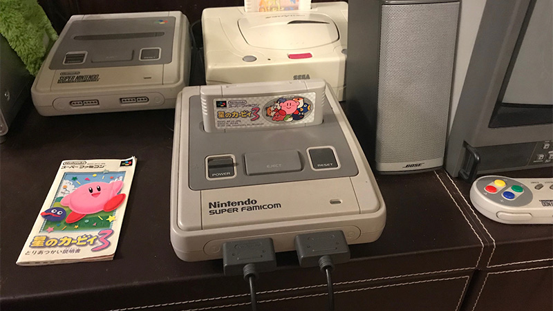Super Famicom console with Kirby's Dreamland 3 cartridge inserted and Japanese manual