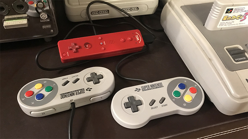 Two SNES-style Classic Controllers beside a red Wii Remote and Super Famicom